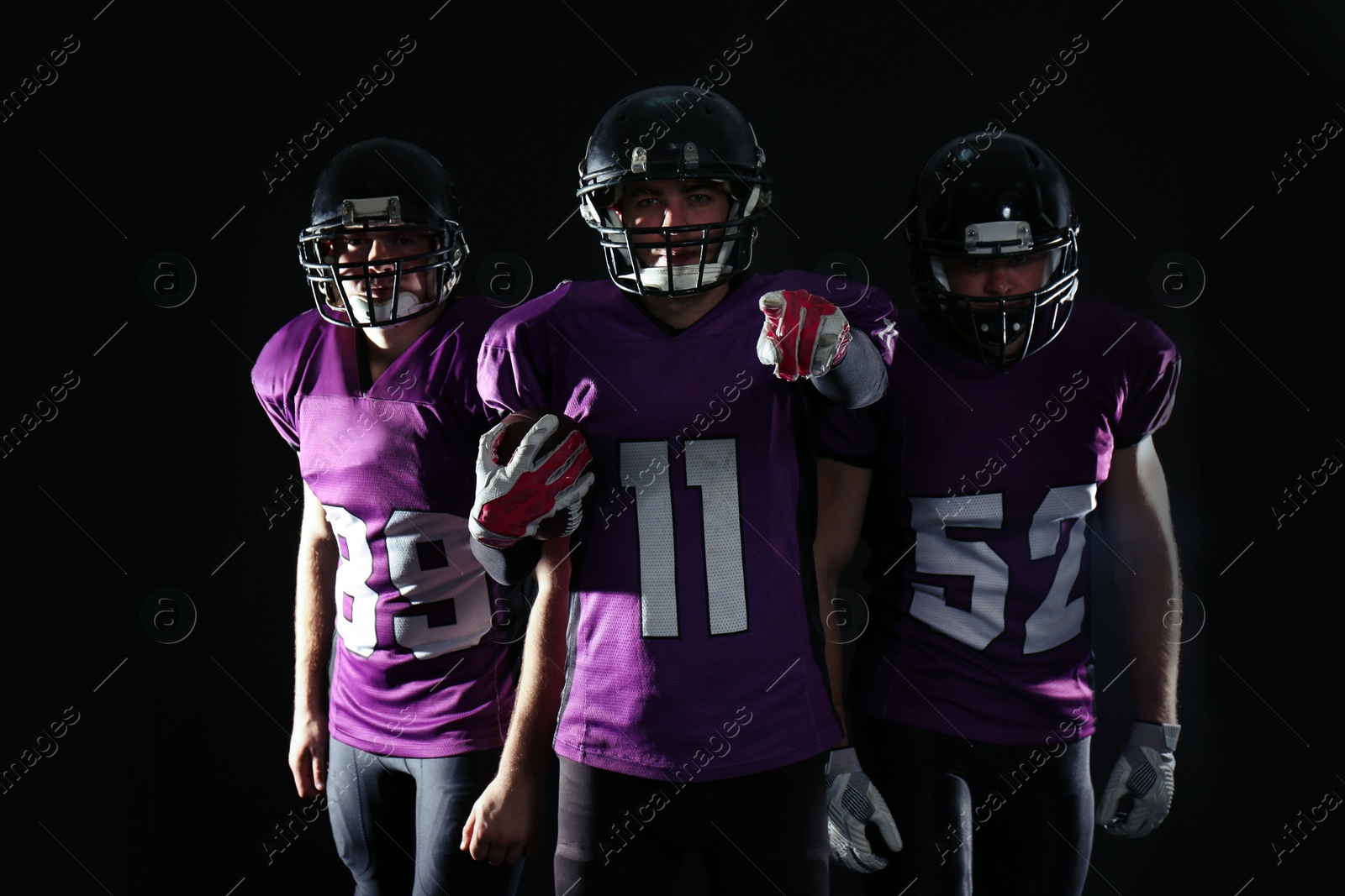 Photo of American football players in uniform on dark background