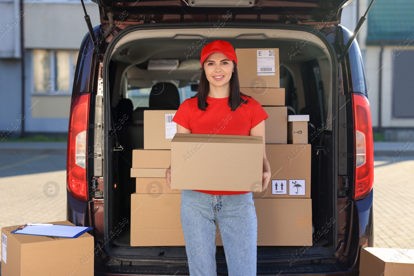 Photo of Courier with parcel near delivery van outdoors