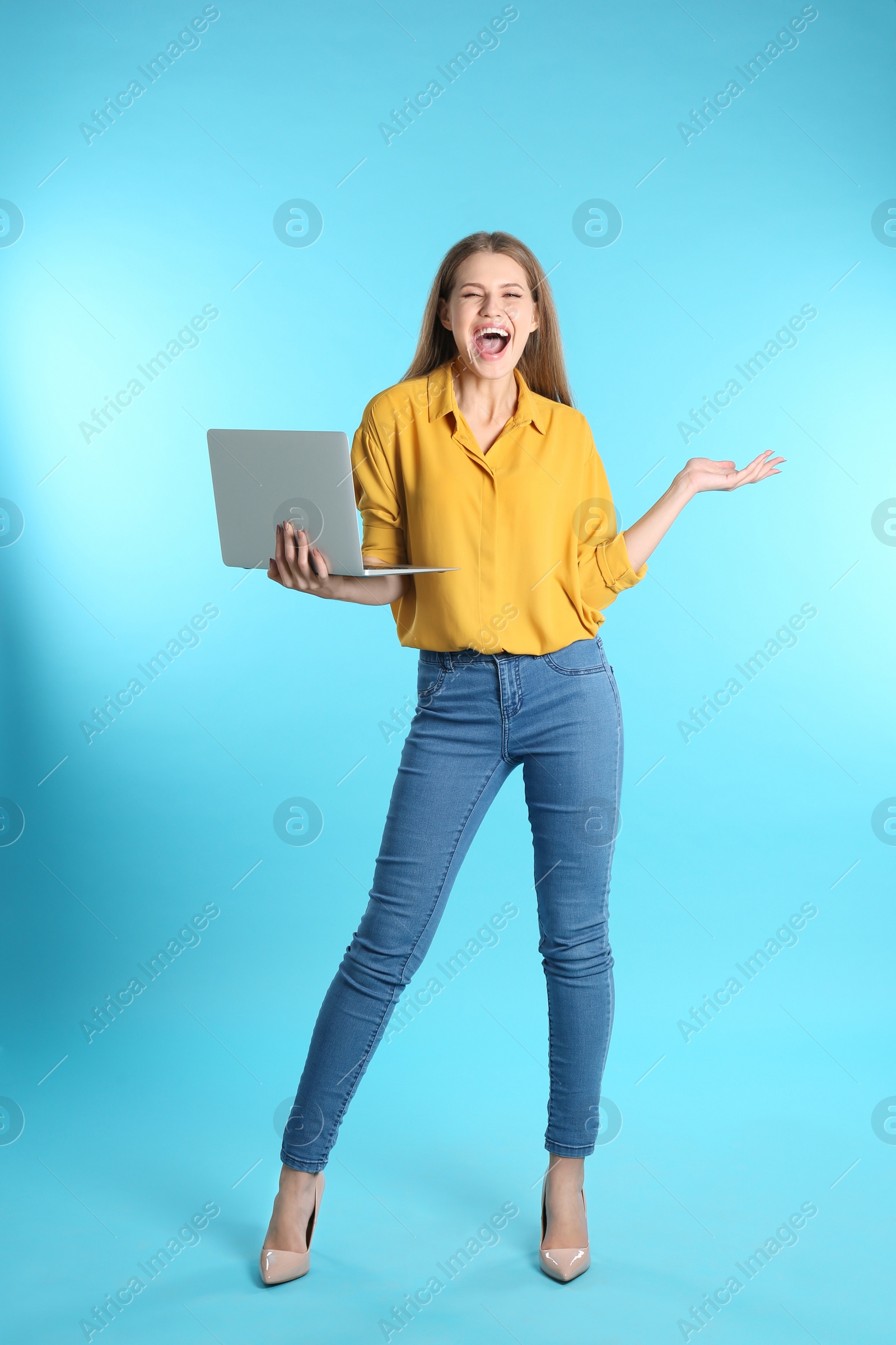 Photo of Emotional young woman with laptop celebrating victory on color background