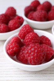 Photo of Tasty ripe raspberries on white wooden table, closeup