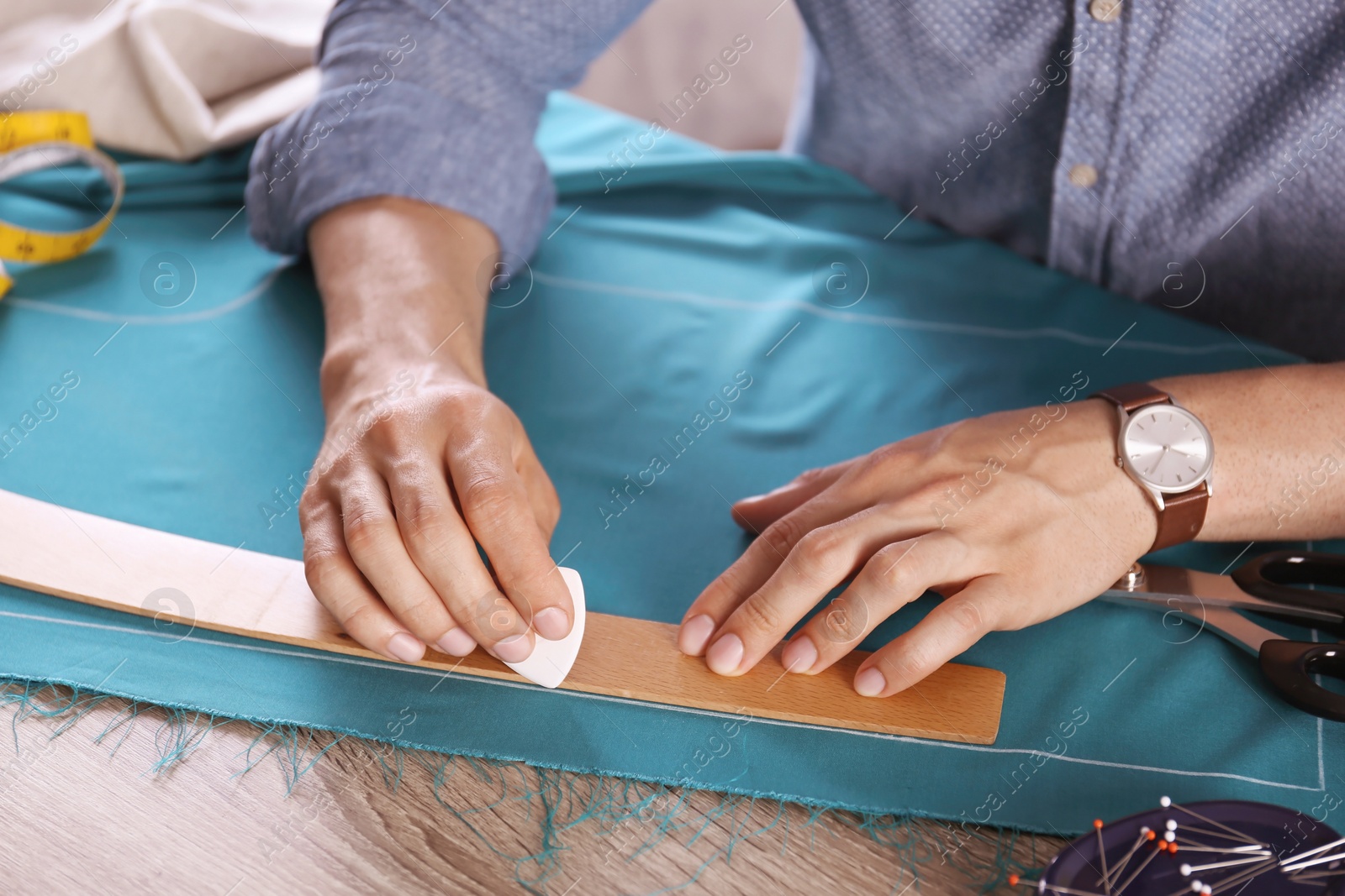 Photo of Tailor working with cloth at table in atelier