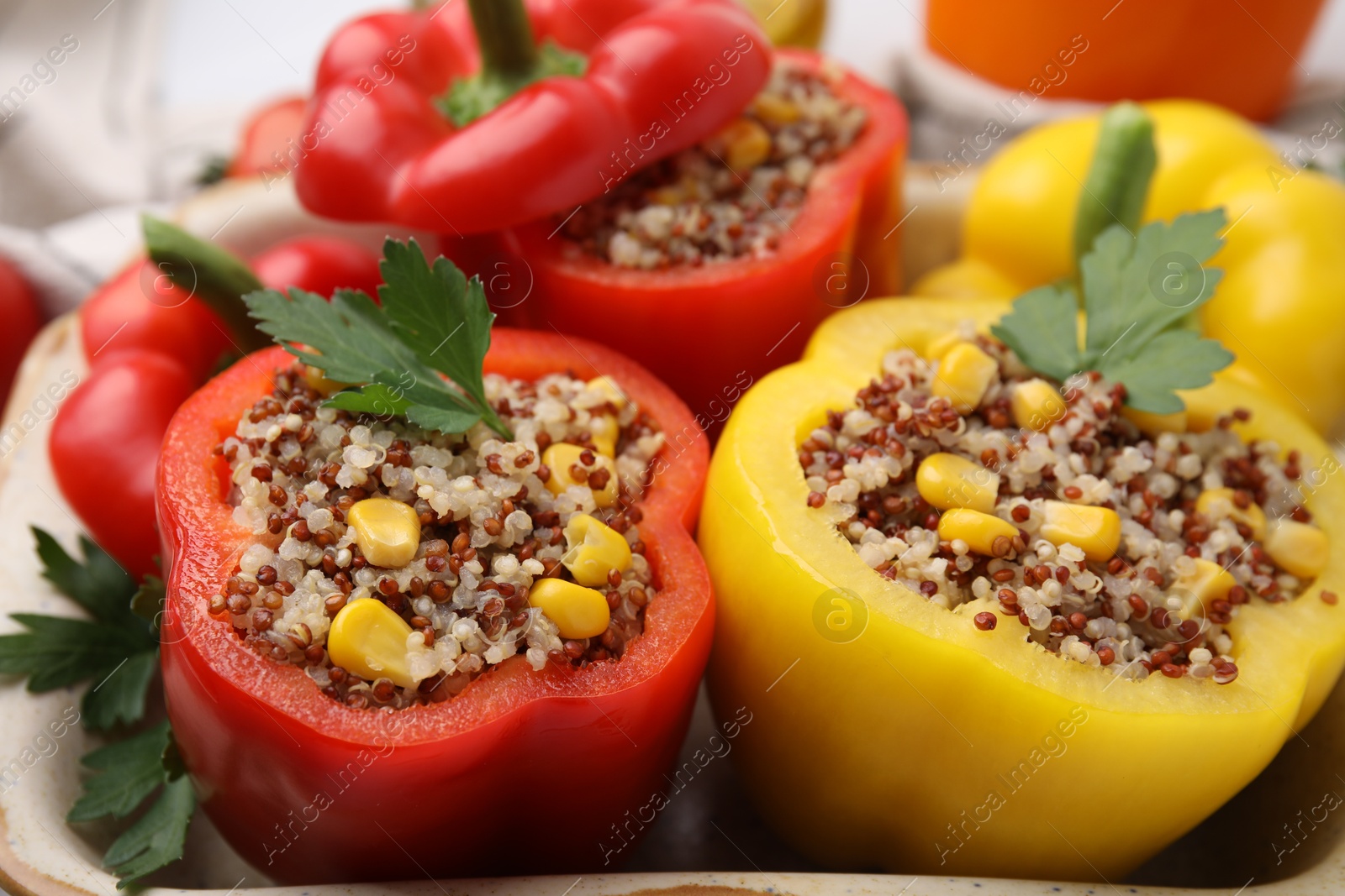 Photo of Quinoa stuffed bell peppers and parsley in baking dish, closeup