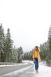 Young woman walking near snowy forest. Winter vacation