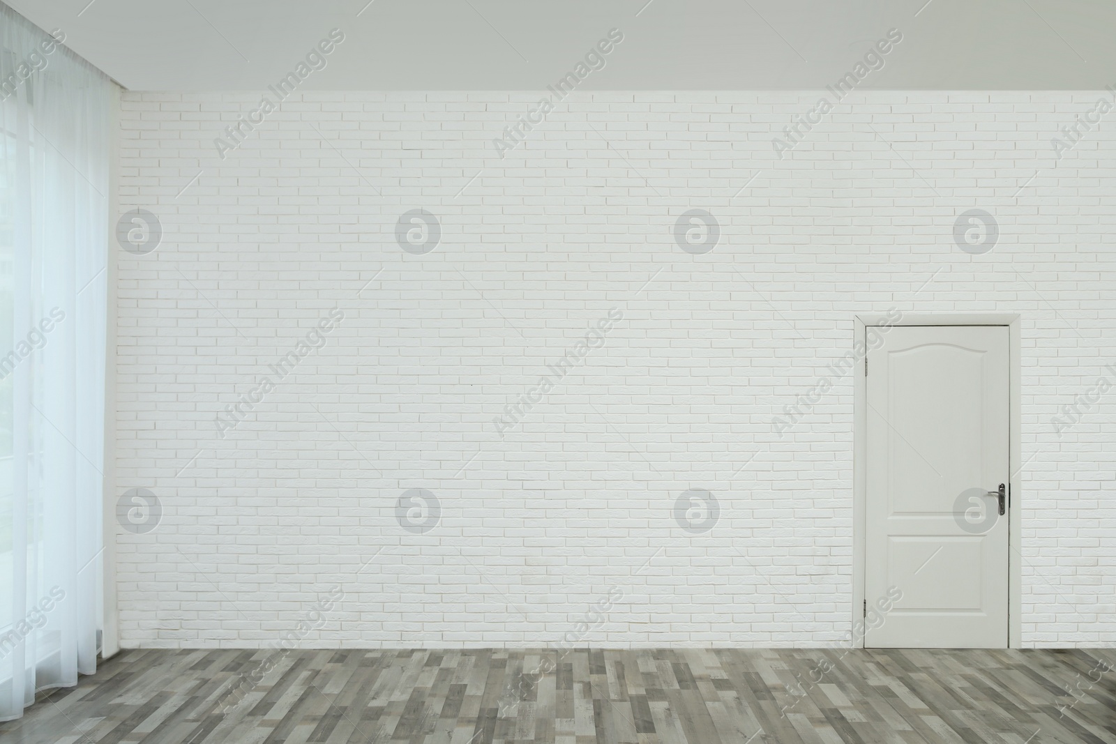 Photo of Empty room with brick wall, white door and laminated floor