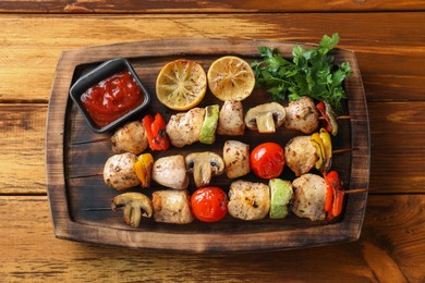 Photo of Delicious shish kebabs with grilled vegetables served on wooden table, top view