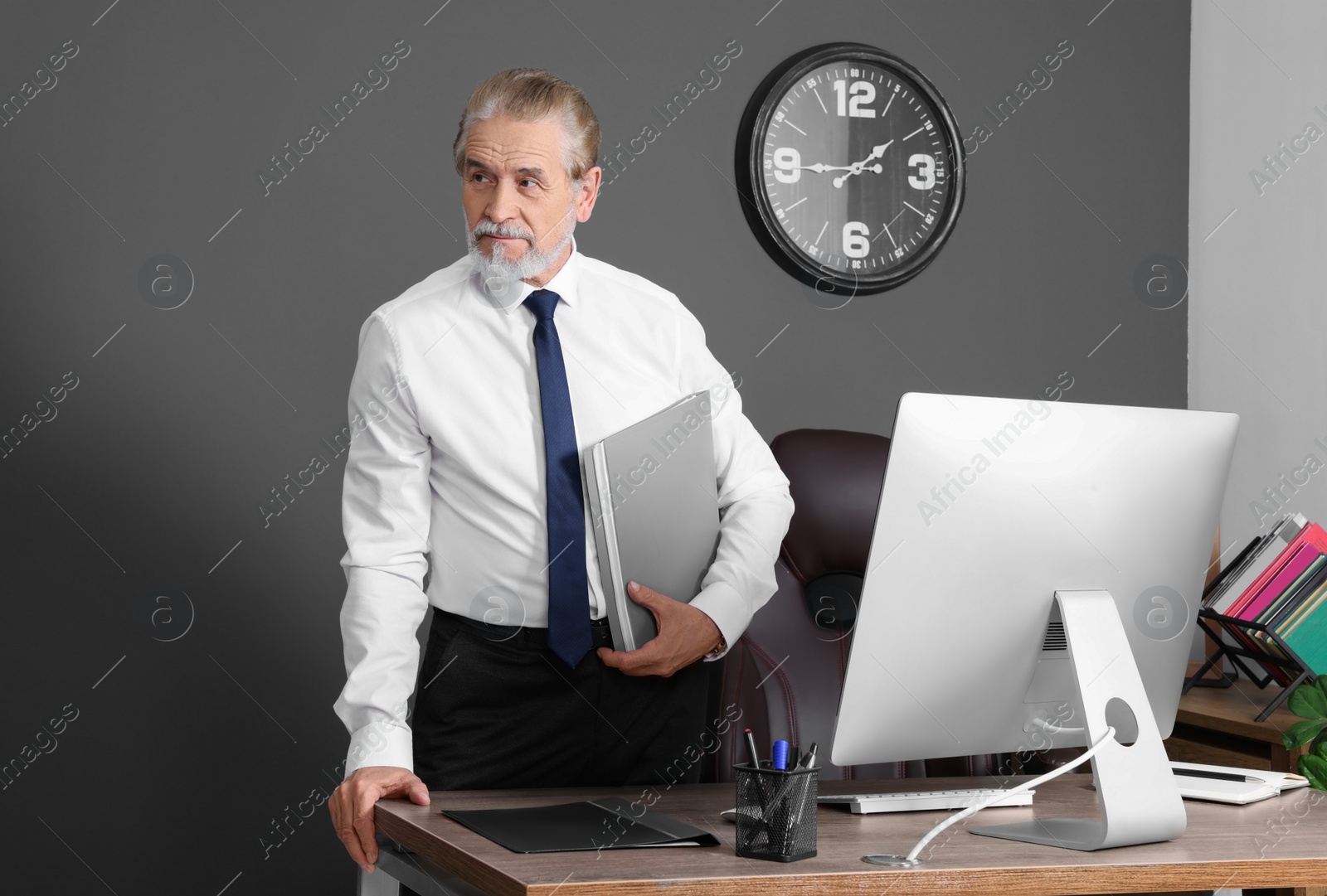 Photo of Senior boss holding clipboard in his modern office