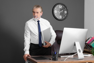 Photo of Senior boss holding clipboard in his modern office