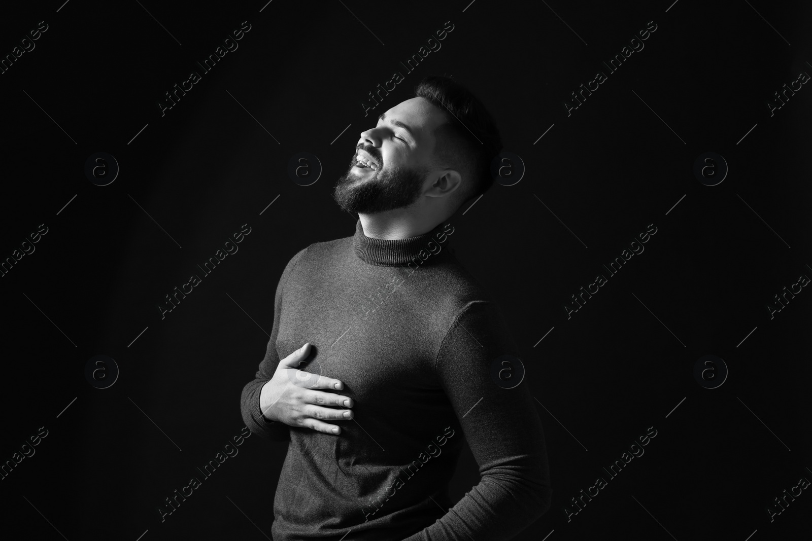 Photo of Portrait of handsome bearded man laughing on dark background, toned in black and white
