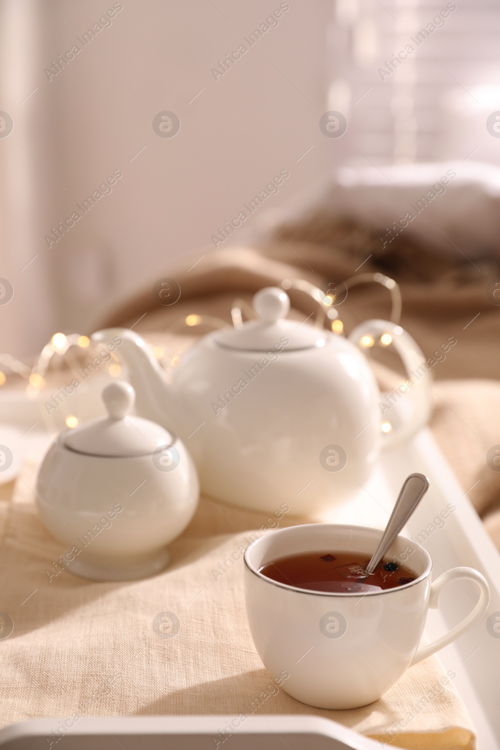 Photo of White tray with ceramic tea set on bed