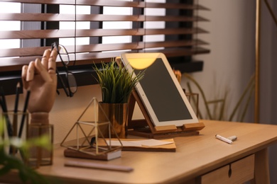 Stylish workplace with different accessories on table at window. Ideas for interior design