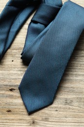 Photo of One blue necktie on light wooden table, top view