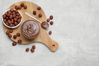 Photo of Bowl with tasty chocolate paste and nuts on light grey table, flat lay. Space for text