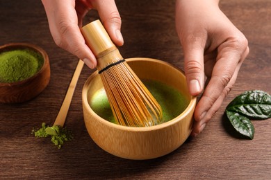 Woman preparing matcha tea at wooden table, closeup