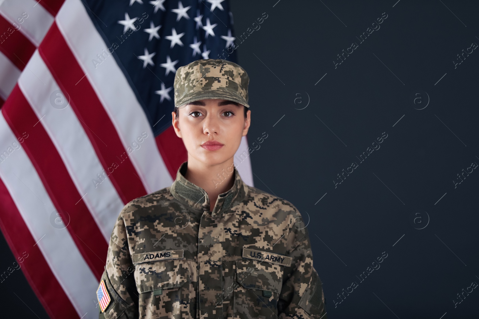 Photo of Female American soldier and flag of USA on dark background. Military service