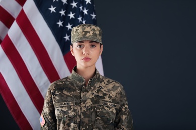 Female American soldier and flag of USA on dark background. Military service