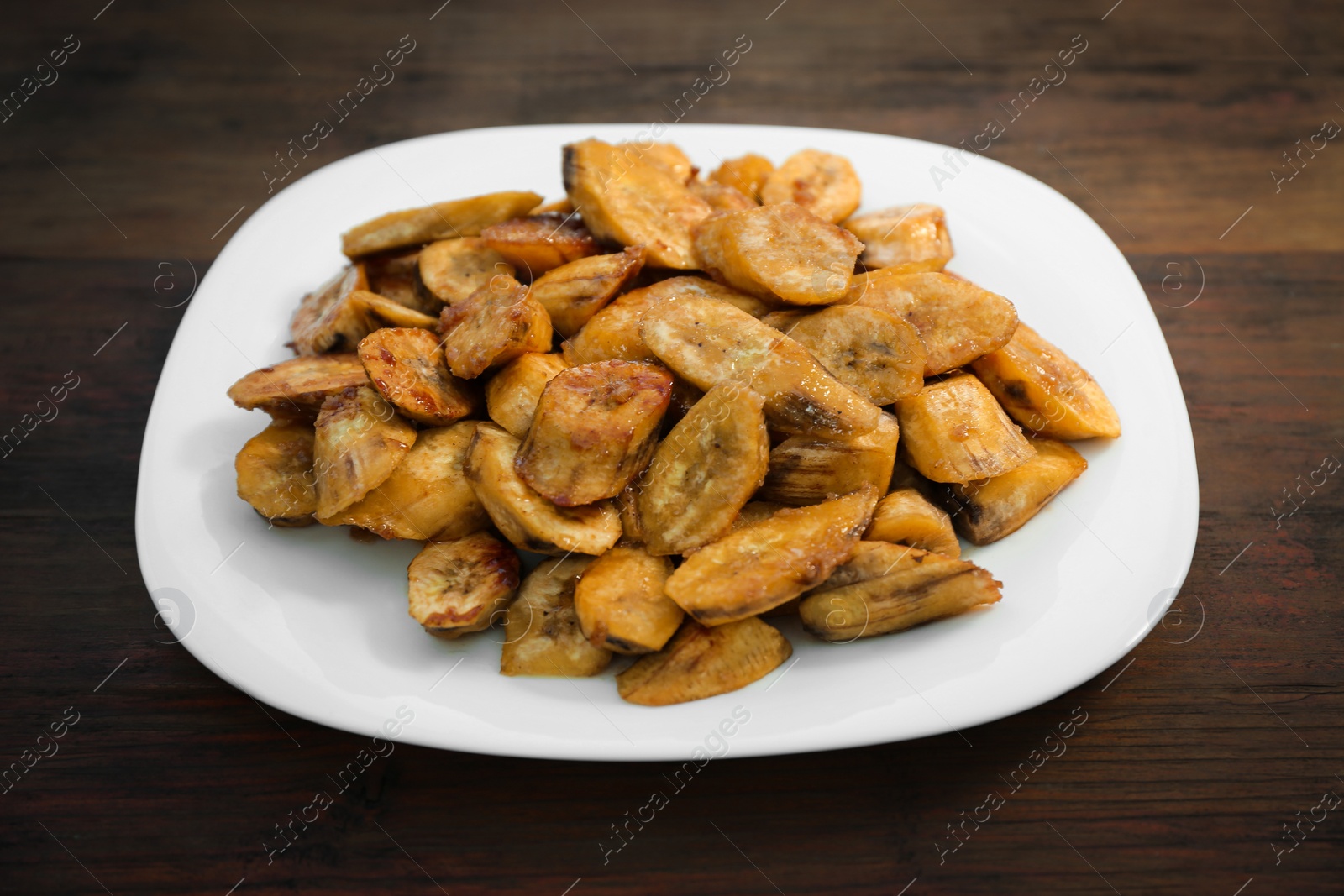 Photo of Tasty deep fried banana slices on wooden table