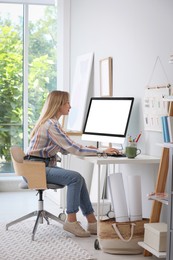 Young woman working on computer at table in room