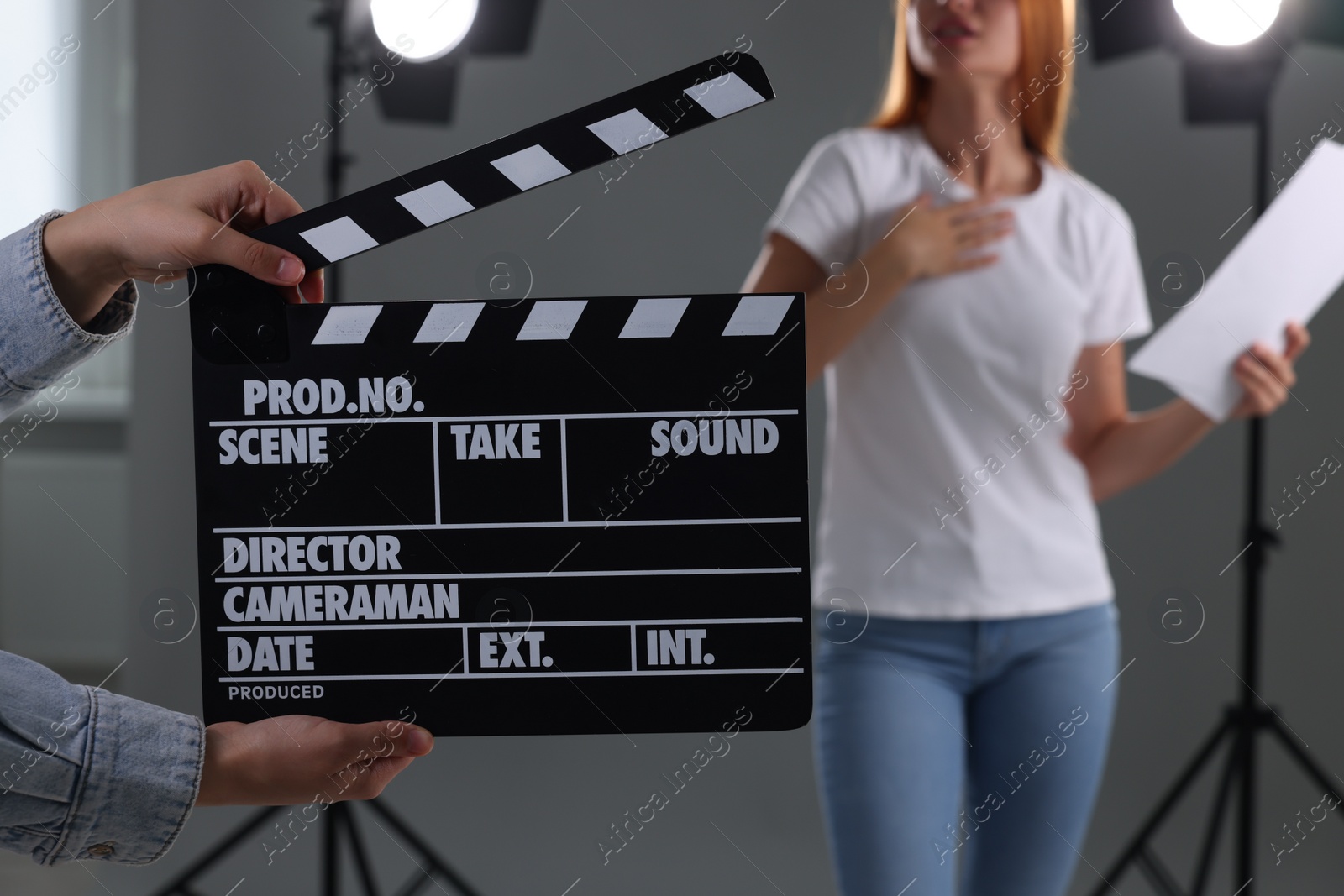 Photo of Casting call. Young woman performing while second assistance camera holding clapperboard against grey background in studio, closeup