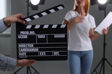 Casting call. Young woman performing while second assistance camera holding clapperboard against grey background in studio, closeup