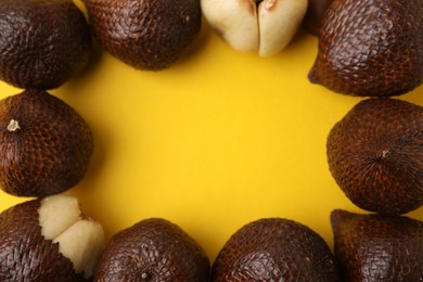 Frame of fresh salak fruits on yellow background, flat lay. Space for text