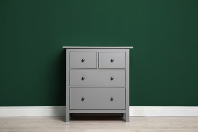 Photo of Modern grey chest of drawers near green wall indoors