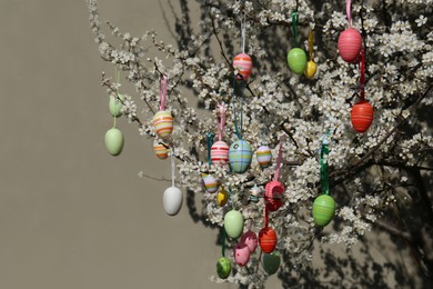 Beautifully painted Easter eggs hanging on blooming cherry tree outdoors