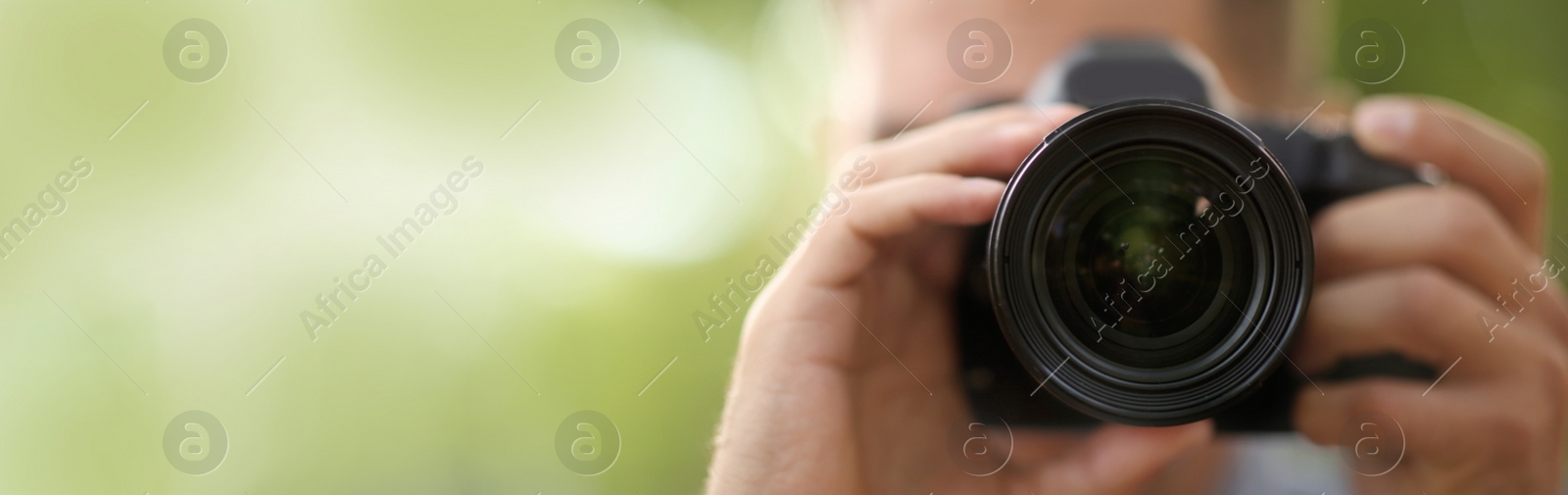 Image of Photographer taking picture with professional camera outdoors, space for text. Banner design