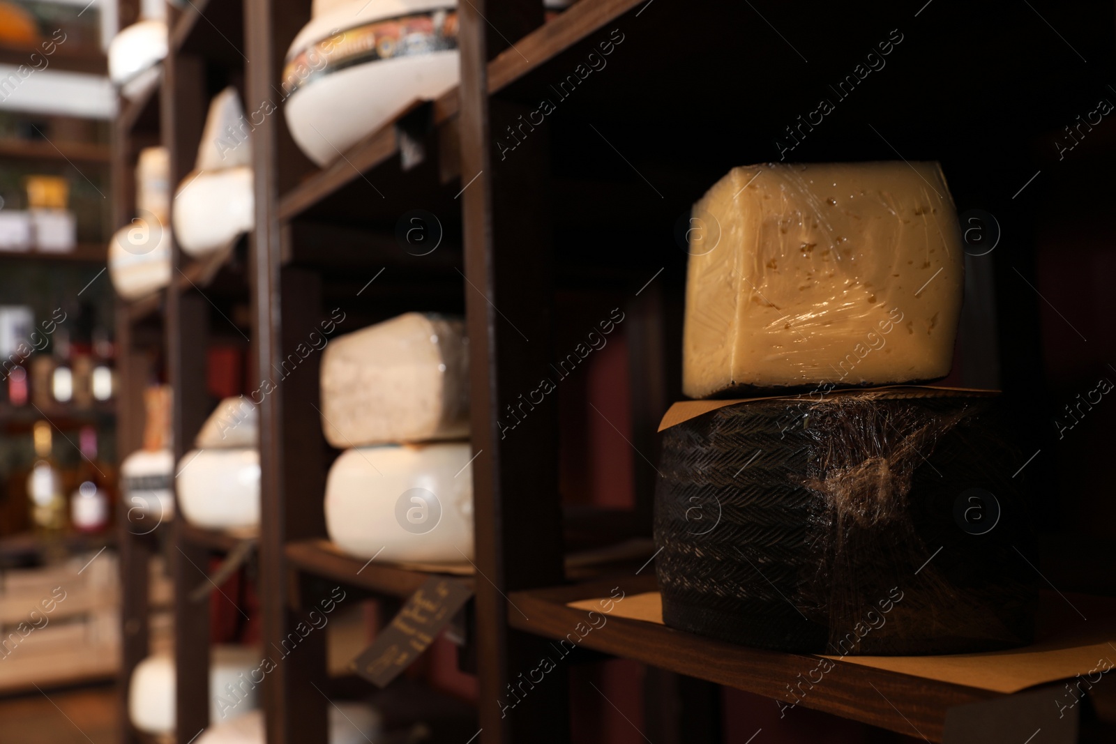 Photo of Different types of delicious cheeses on rack in store