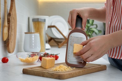 Photo of Woman grating cheese at kitchen counter, closeup