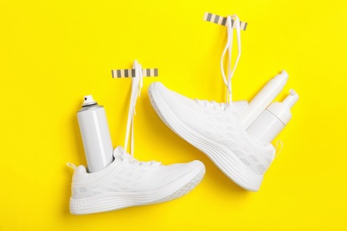 Stylish footwear with shoe care accessories hanging on yellow background