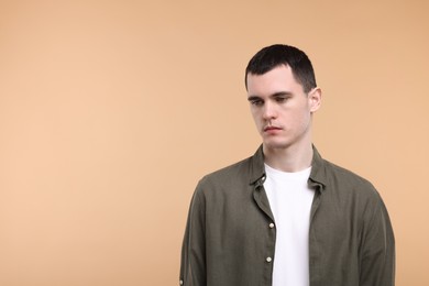 Portrait of sad man on beige background, space for text