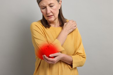 Arthritis symptoms. Woman suffering from pain in her elbow on grey background