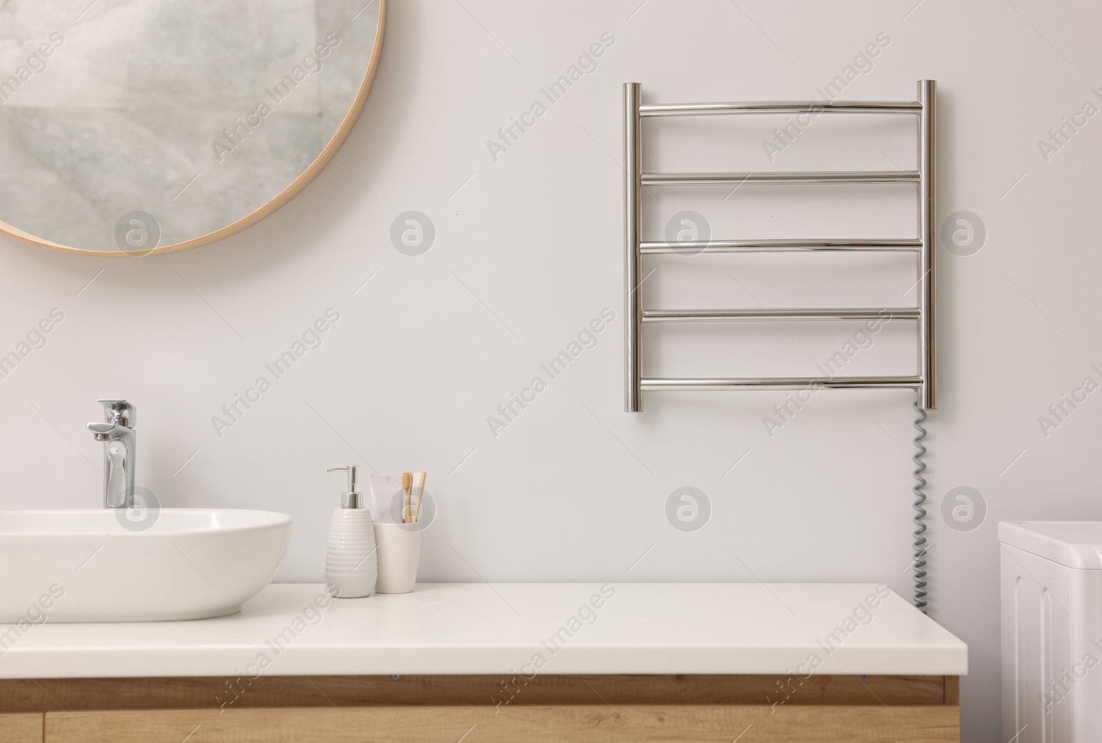 Photo of Heated towel rail on white wall in bathroom