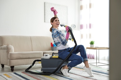 Photo of Happy woman having fun while cleaning room