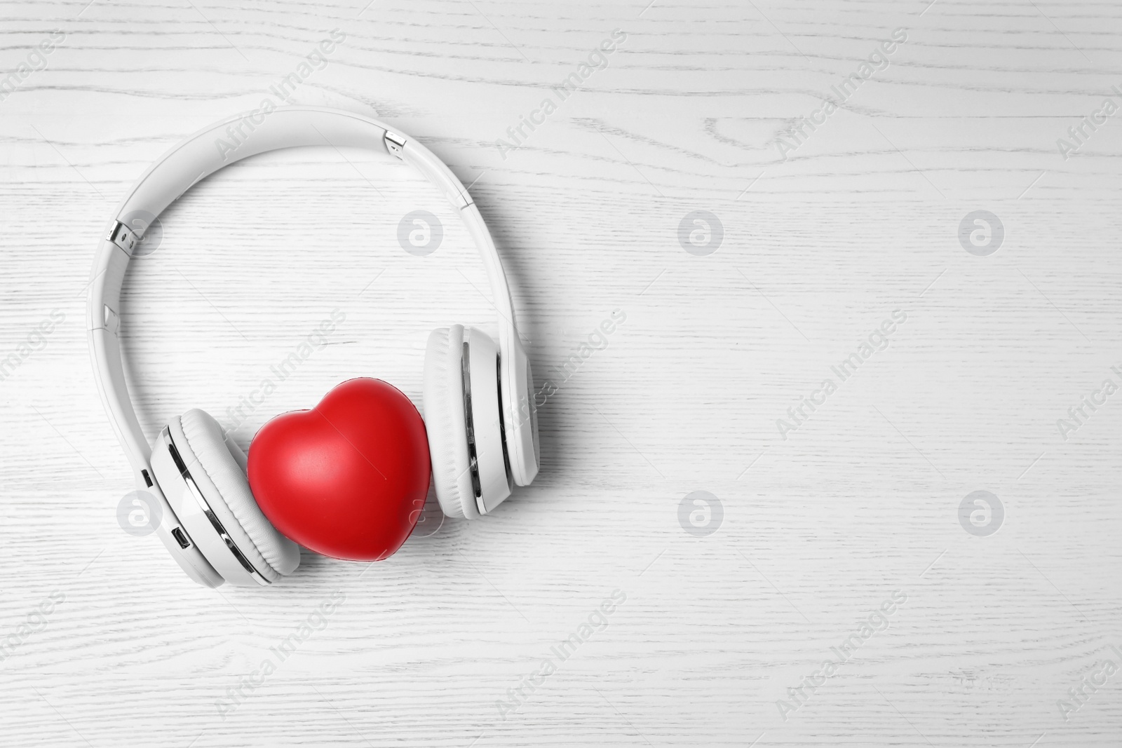 Photo of Headphones, heart and space for text on white wooden background, top view