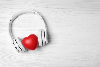 Photo of Headphones, heart and space for text on white wooden background, top view