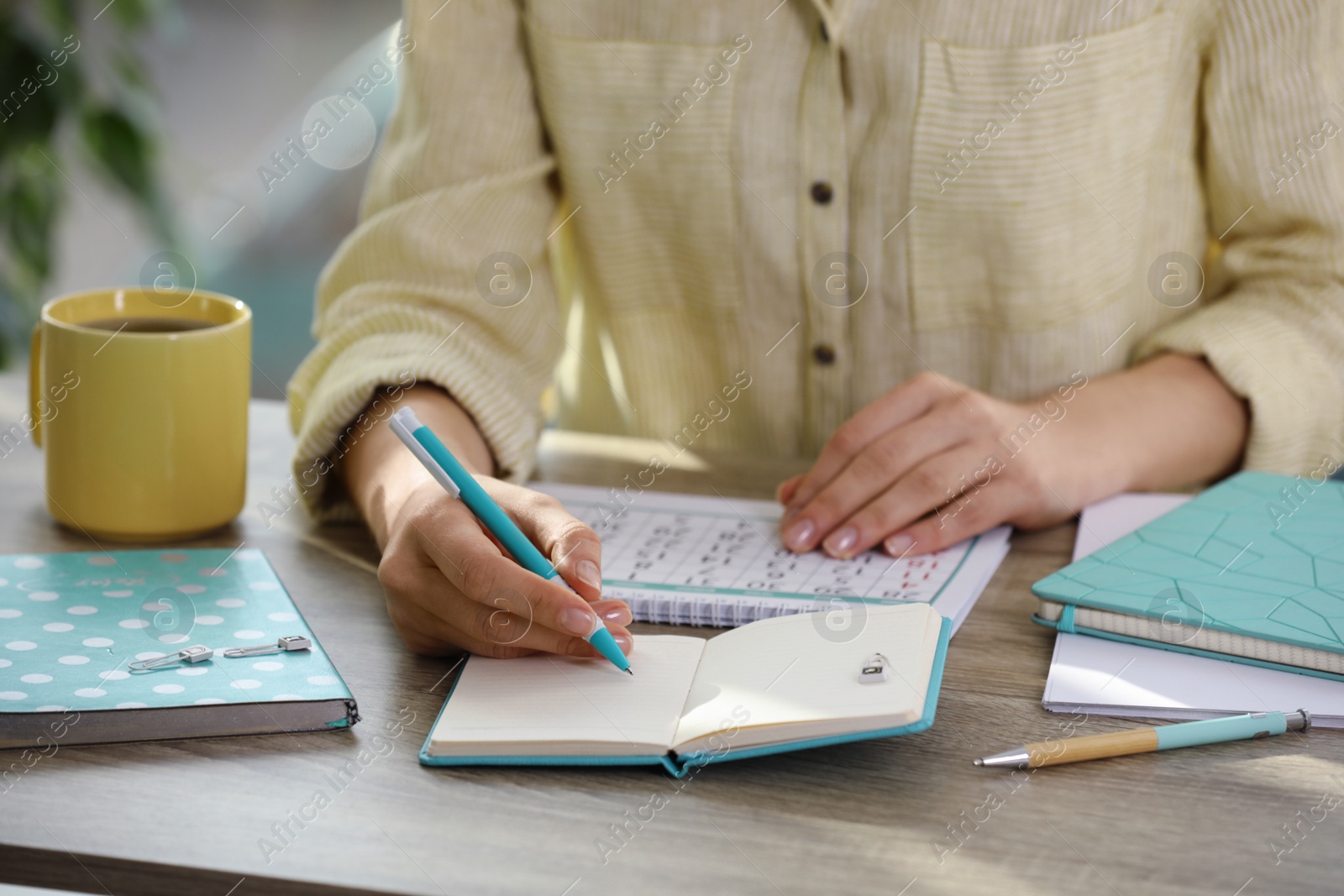 Photo of Woman making schedule using calendar at wooden table, closeup