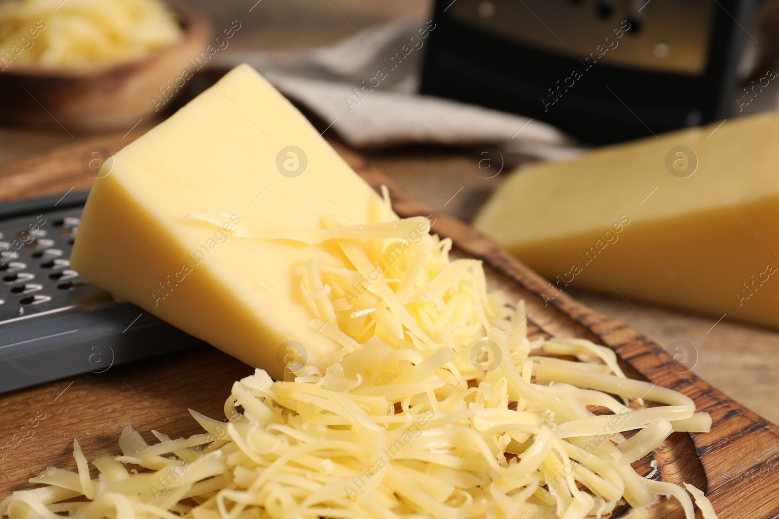 Photo of Grated and whole pieces of cheese on wooden table, closeup