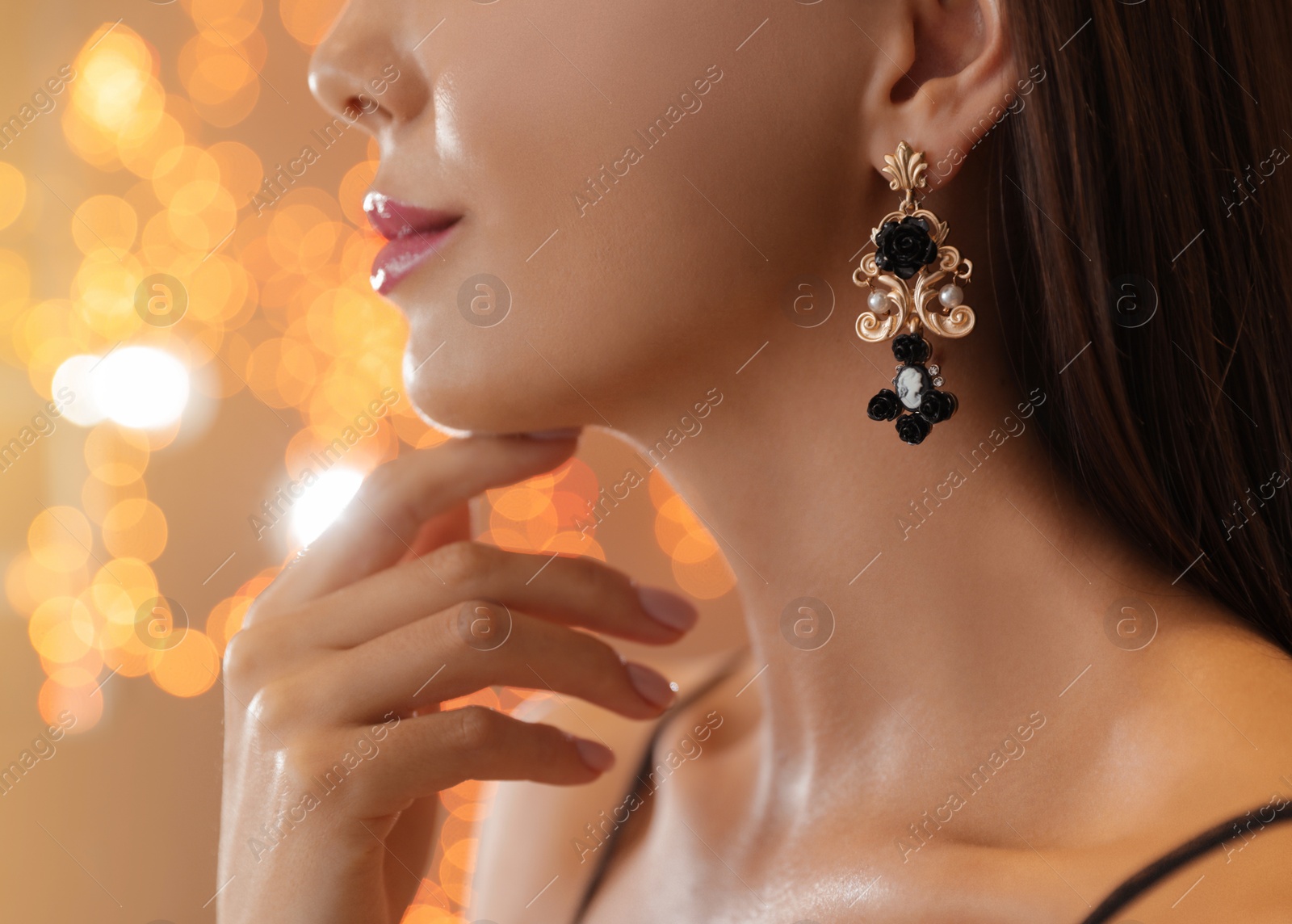 Photo of Beautiful young woman with elegant jewelry against defocused lights, closeup. Space for text