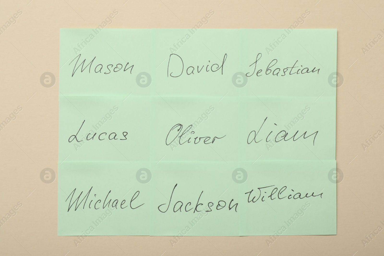 Photo of Paper stickers with different names on beige background, top view. Choosing baby's name