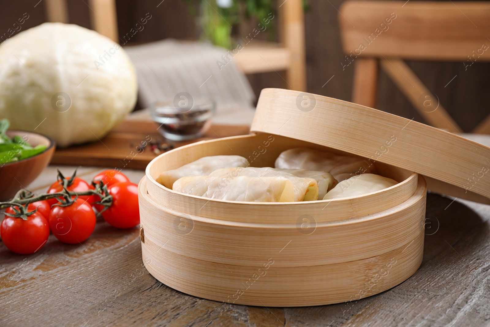 Photo of Delicious cabbage rolls in bamboo steamer on wooden table indoors