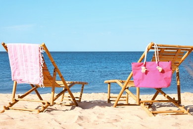 Empty wooden sunbeds and beach accessories on sandy shore