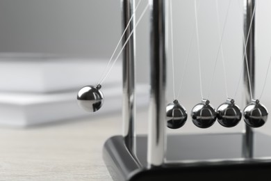 Photo of Newton's cradle on wooden table, closeup. Physics law of energy conservation