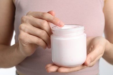 Photo of Woman holding jar of hand cream, closeup