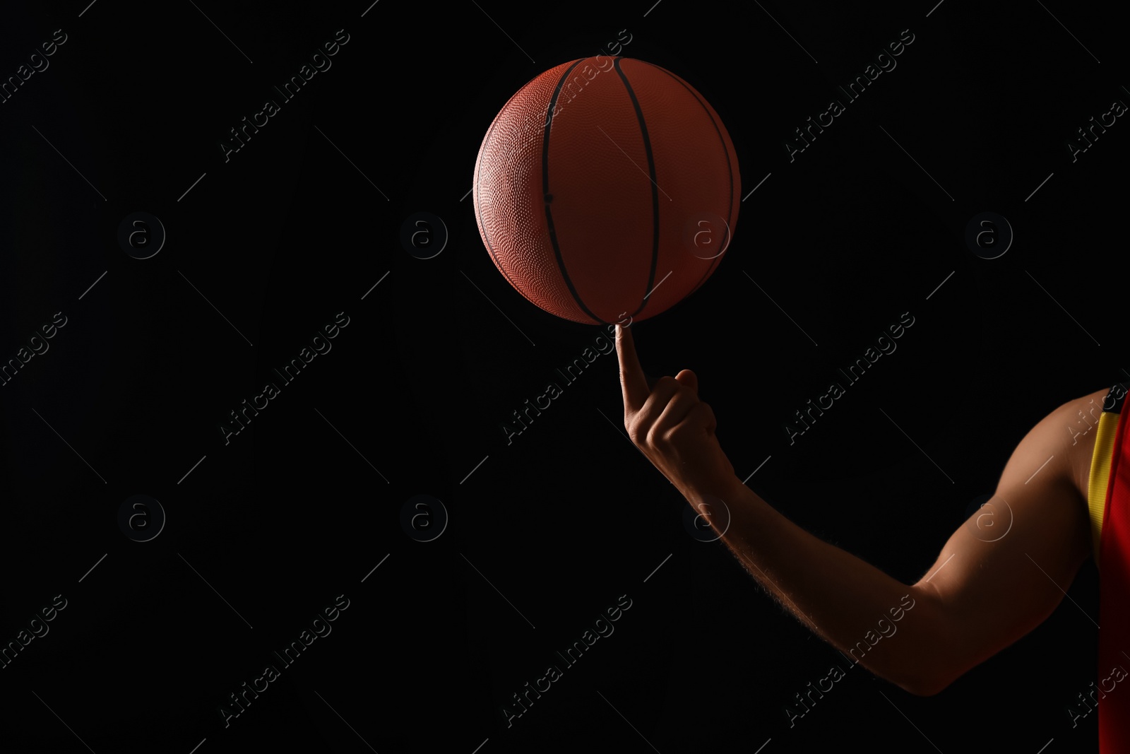Photo of Basketball player with spinning ball on black background, closeup. Space for text