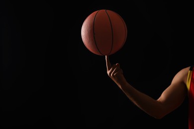 Photo of Basketball player with spinning ball on black background, closeup. Space for text
