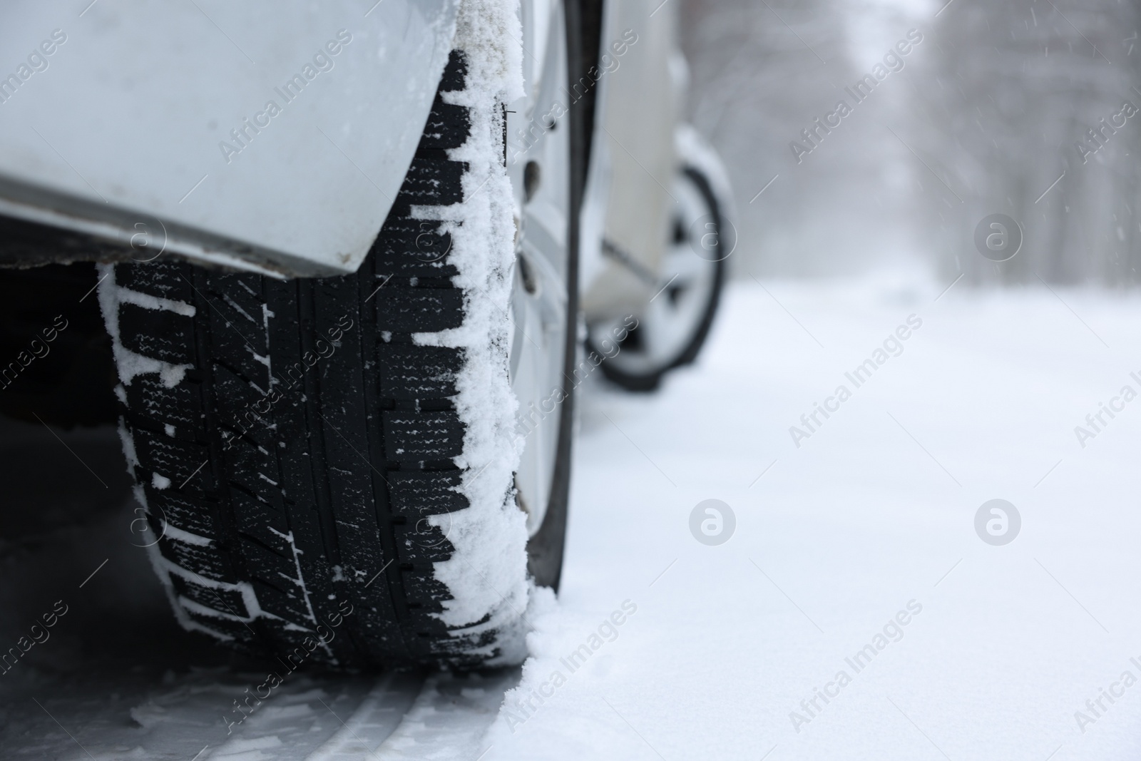 Photo of Car with winter tires on snowy road outdoors, closeup. Space for text