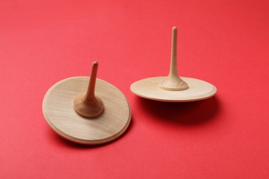 Photo of Two wooden spinning tops on red background