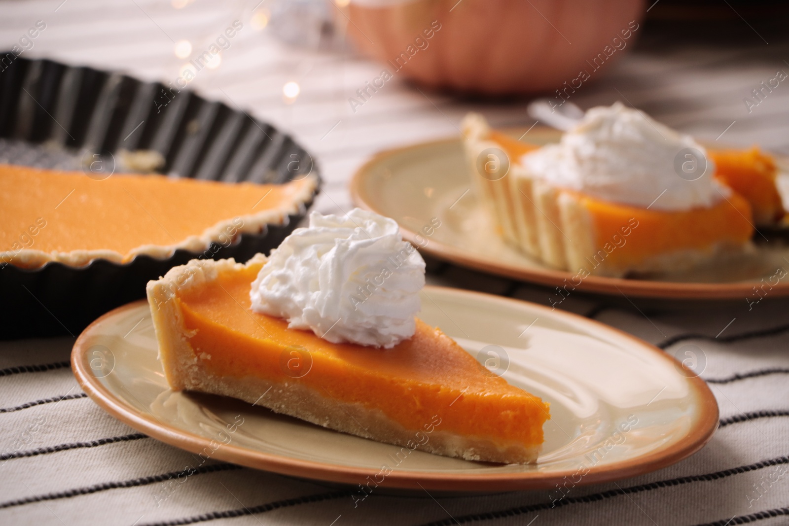 Photo of Fresh homemade pumpkin pie with whipped cream on table