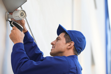 Photo of Technician installing CCTV camera on wall outdoors